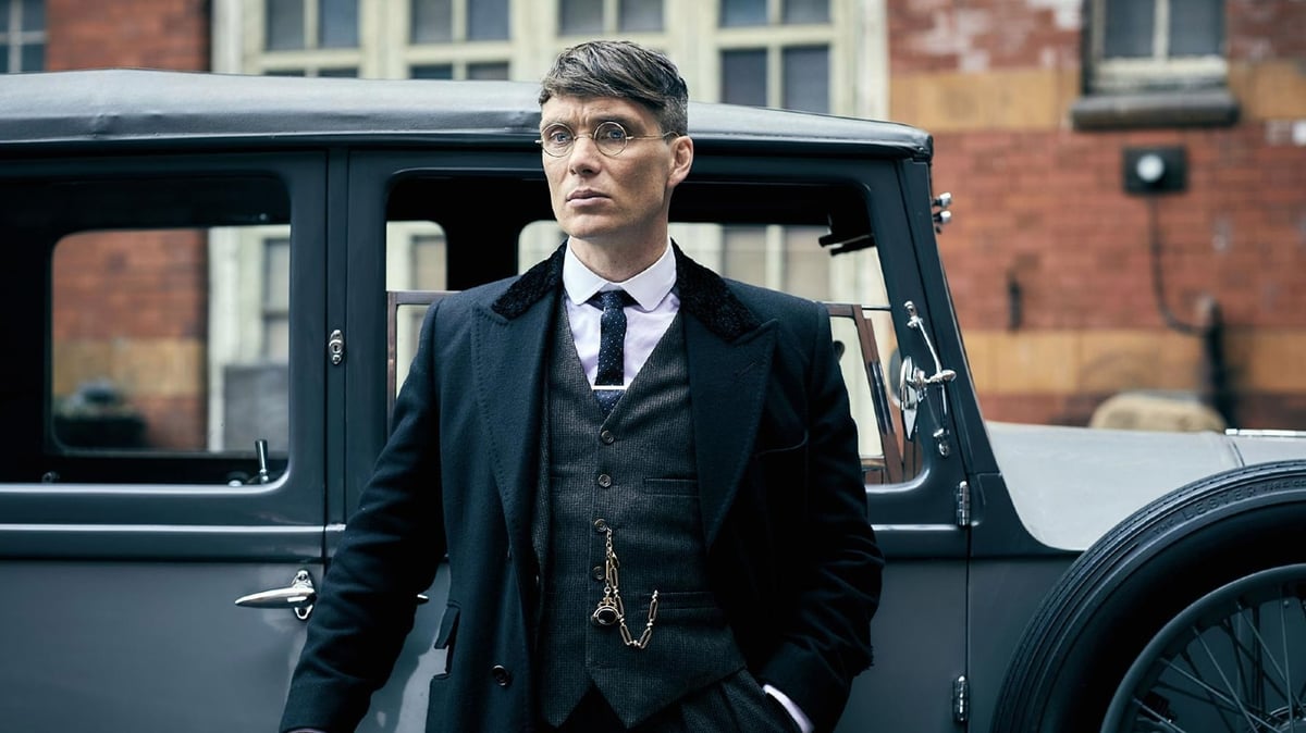 A person wearing a suit and tie standing in front of a car