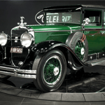 A green truck parked in front of a car