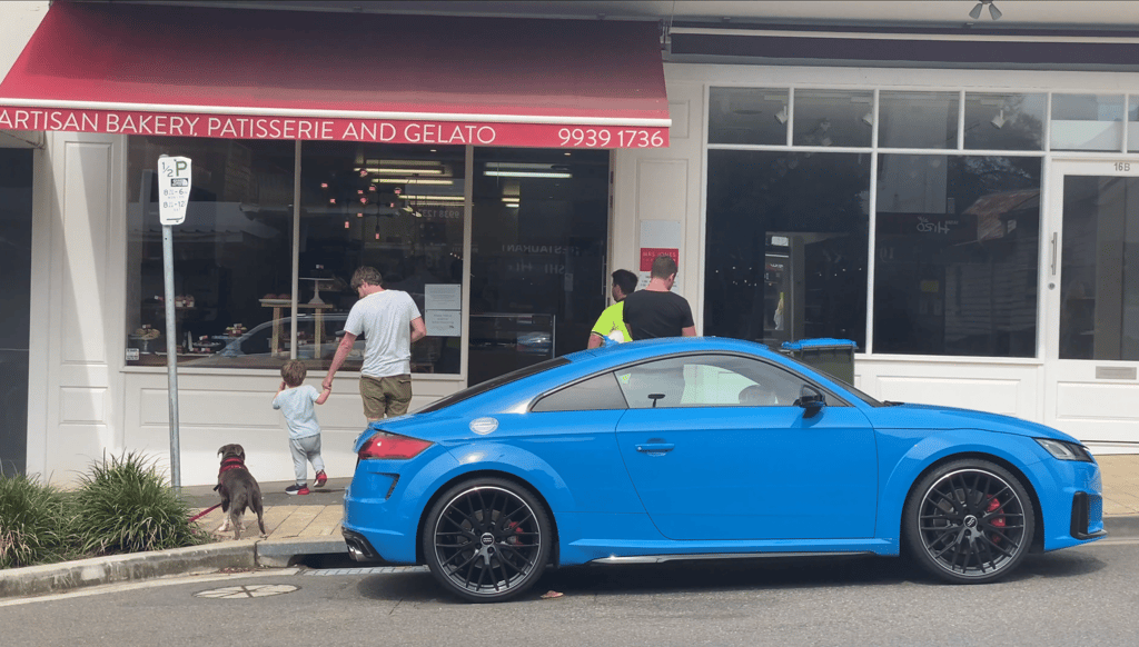 A person in a blue car parked in front of a store
