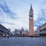 A large clock tower towering over the city of london with Piazza San Marco in the background