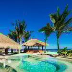 A beach with palm trees and a pool of water
