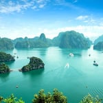 A small boat in a body of water with Ha Long Bay in the background