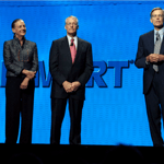 A group of people standing next to a man in a suit and tie