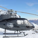 A helicopter flying over a snow covered mountain