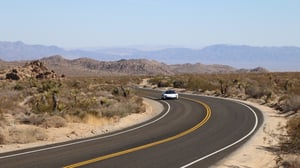 A highway with a mountain in the middle of a desert road