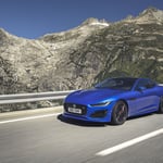 A blue car parked on the side of a mountain road