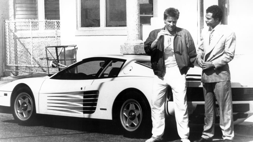 A man standing in front of a car posing for the camera