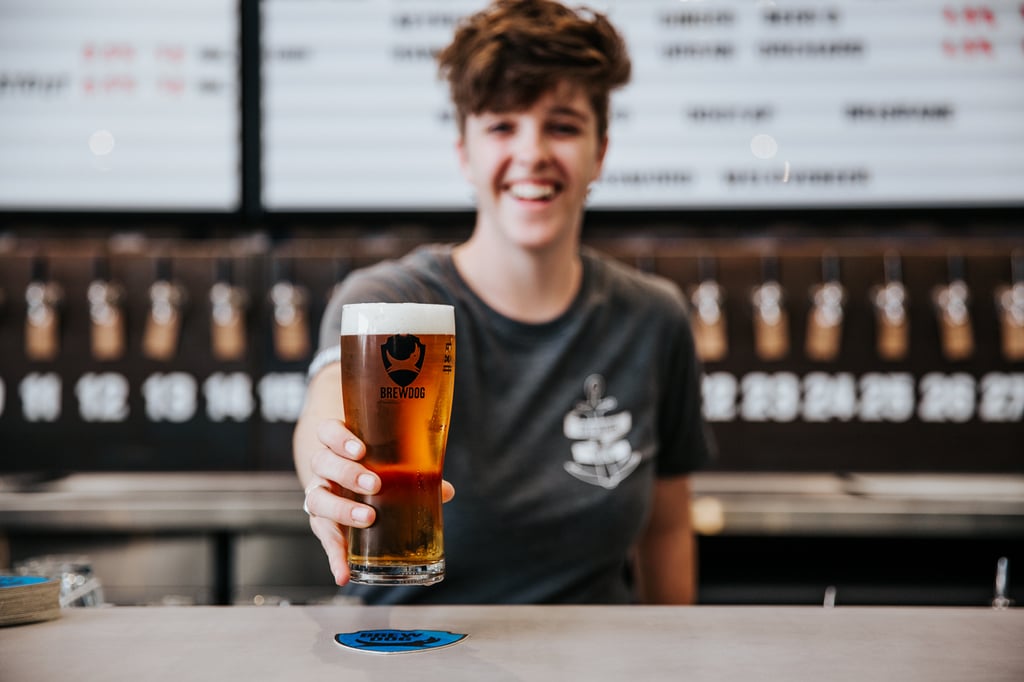 A person sitting at a table with a cup of beer