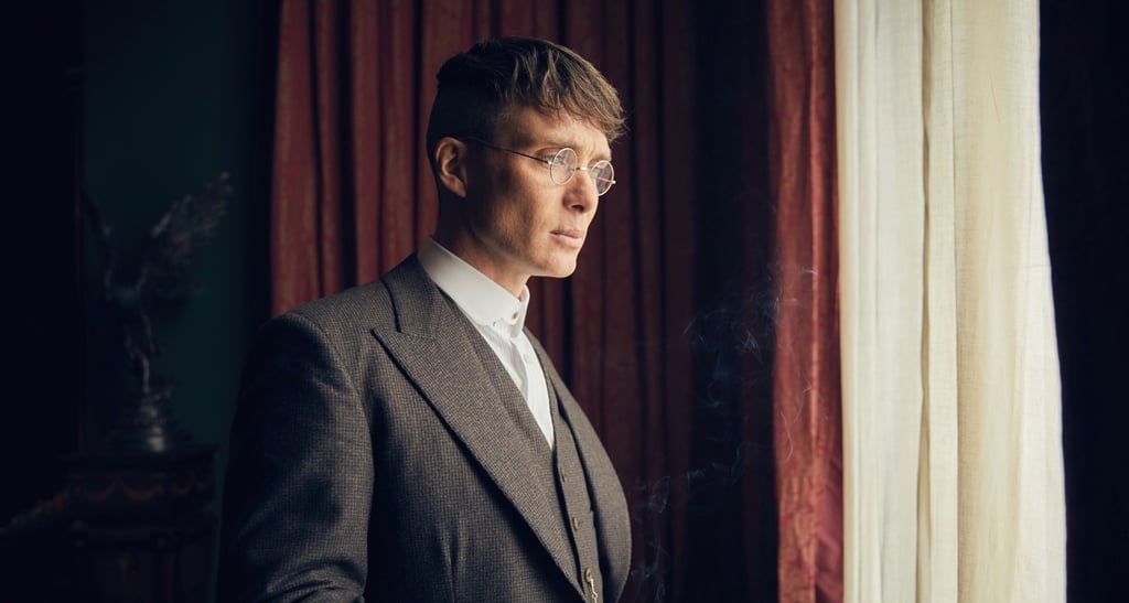 A man wearing a suit and tie standing in front of a curtain