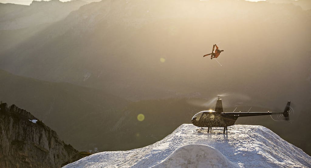 A person flying through the air on top of a mountain