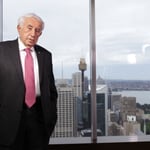 A man wearing a suit and tie standing in front of a window