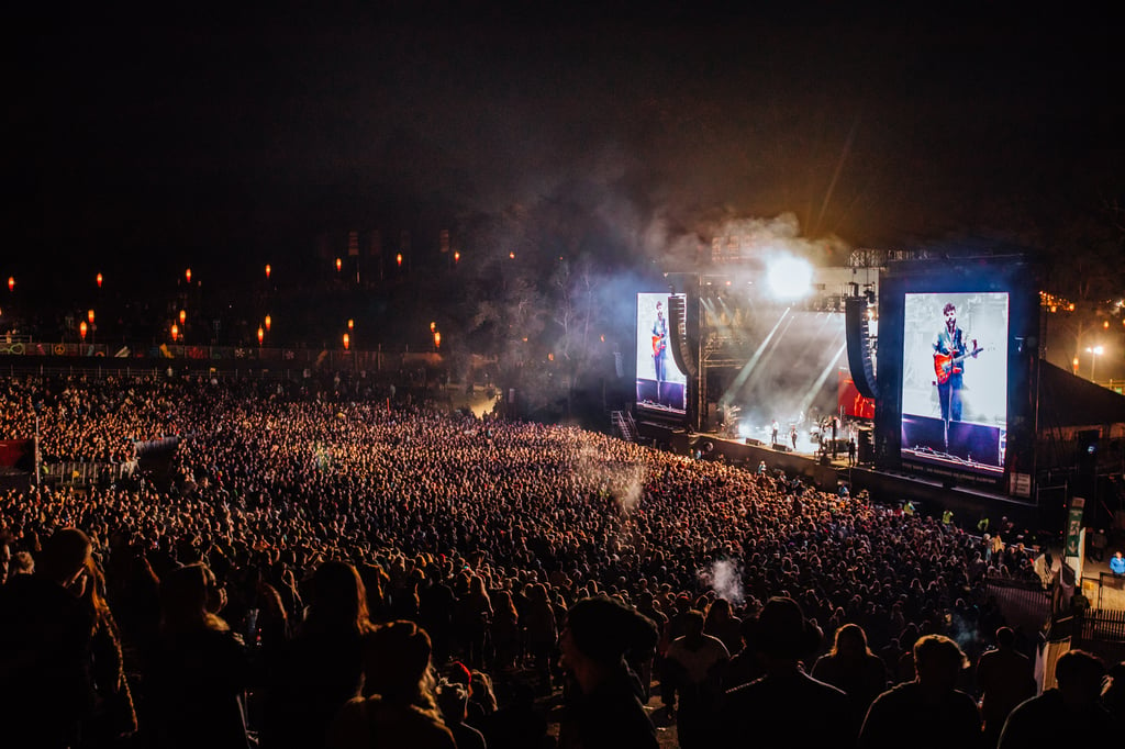 A group of people standing in front of a large crowd at night