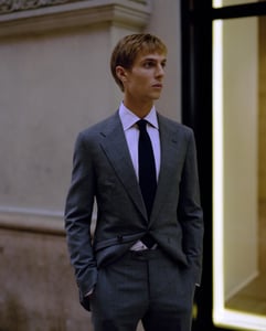 A man wearing a suit and tie standing in front of a building