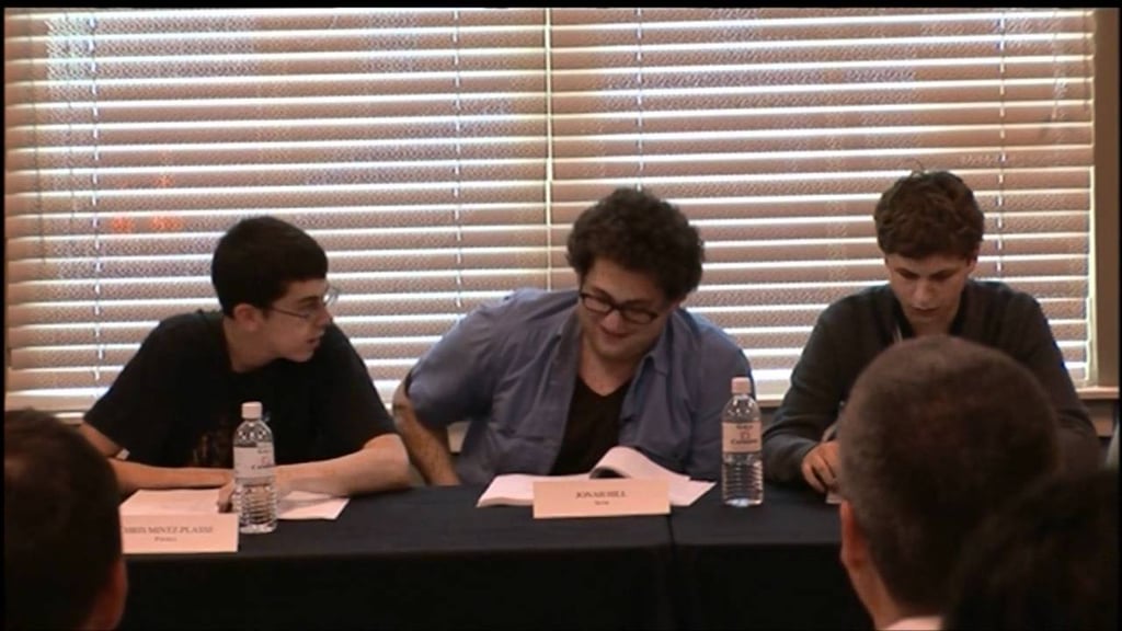 A group of people sitting at a table in front of a window