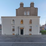 A building with a clock on the side of a road