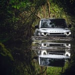 A car parked on pavement near a forest