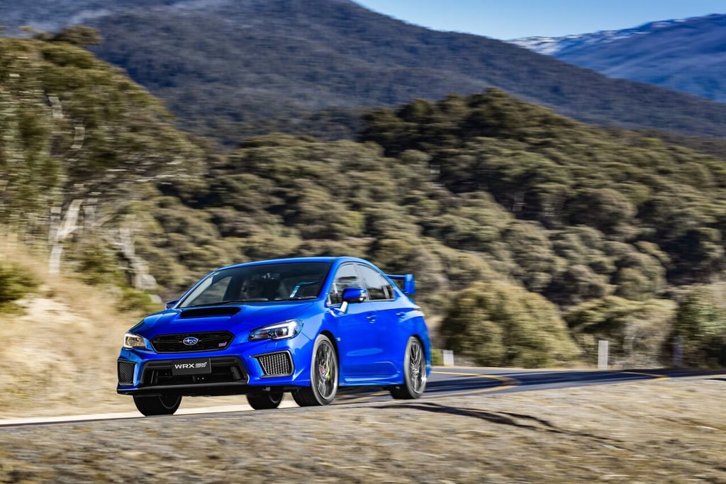 A blue car driving down a dirt road