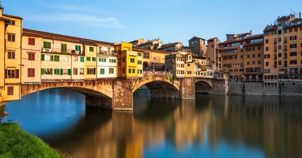 Ponte Vecchio over a body of water with a city in the background