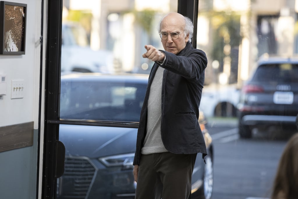 A person standing in front of a car talking on a cell phone