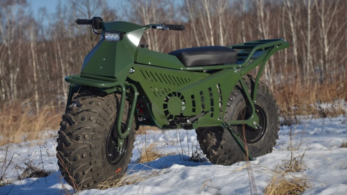 A green motorcycle parked on the side of a snow covered field