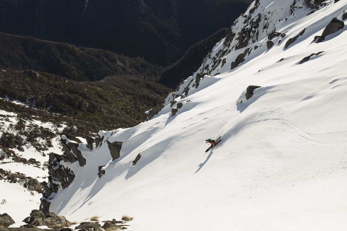 A man skiing down the side of a snow covered mountain