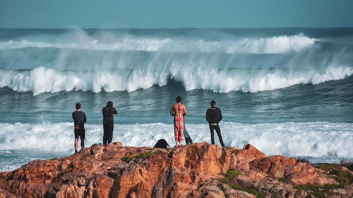 A group of people standing in a rocky area next to water