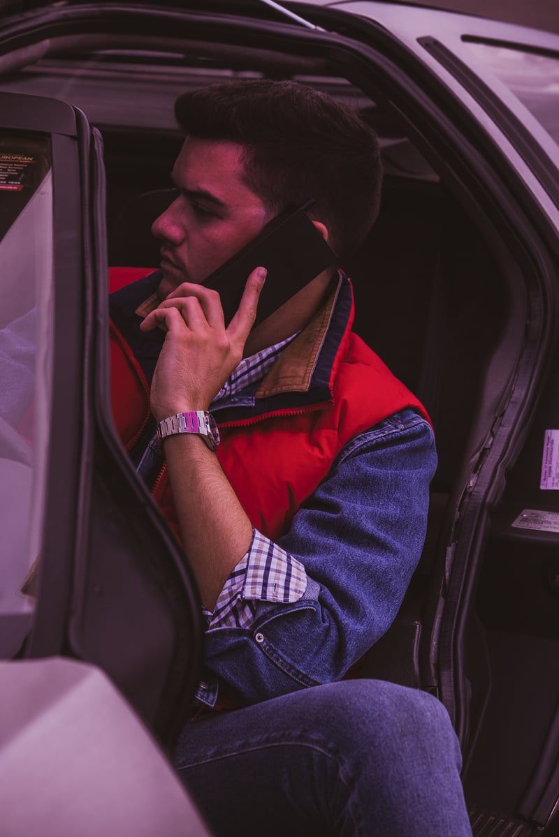 A man sitting in a car talking on a cell phone