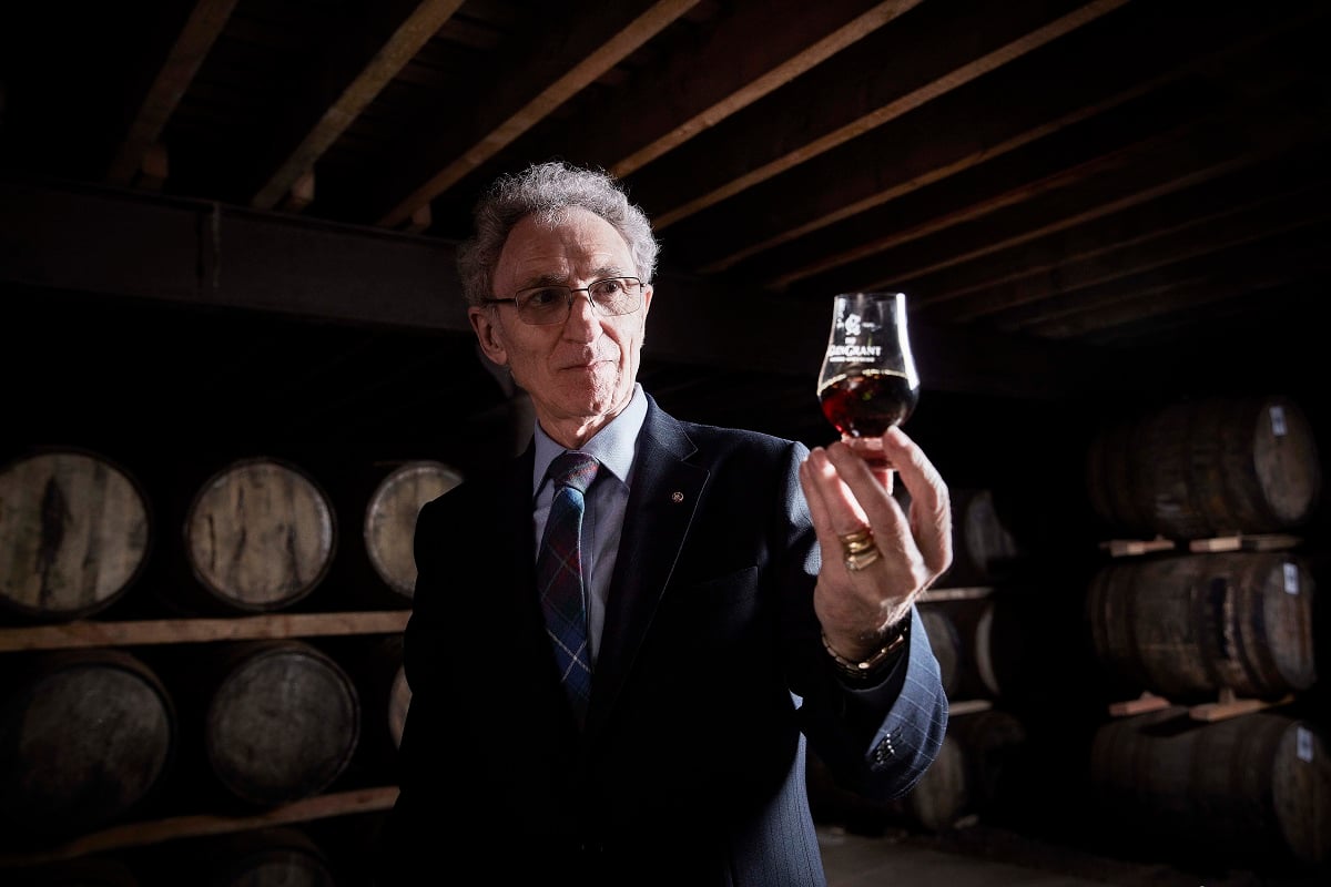 Master Distillery Dennis Malcolm holding a dram of the 60 Year Old whisky released in his name