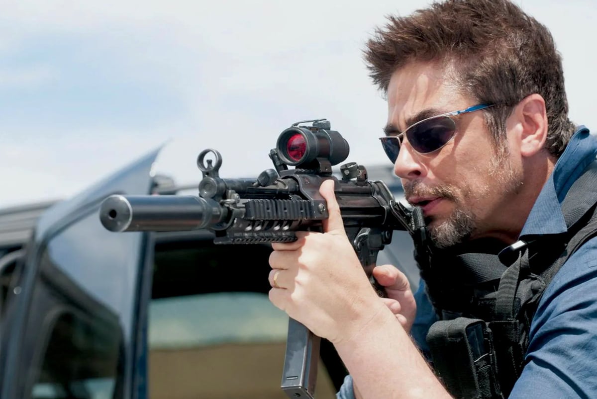 A man wearing sunglasses and holding a gun