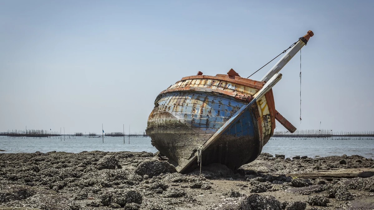 A boat sitting on top of a sandy beach