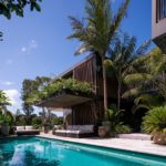 A pool next to a palm tree in front of a building