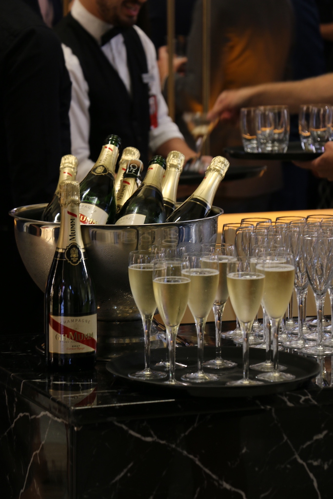 A group of people standing around a table with wine glasses