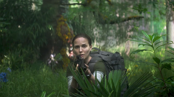 A person holding a plant in front of a tree