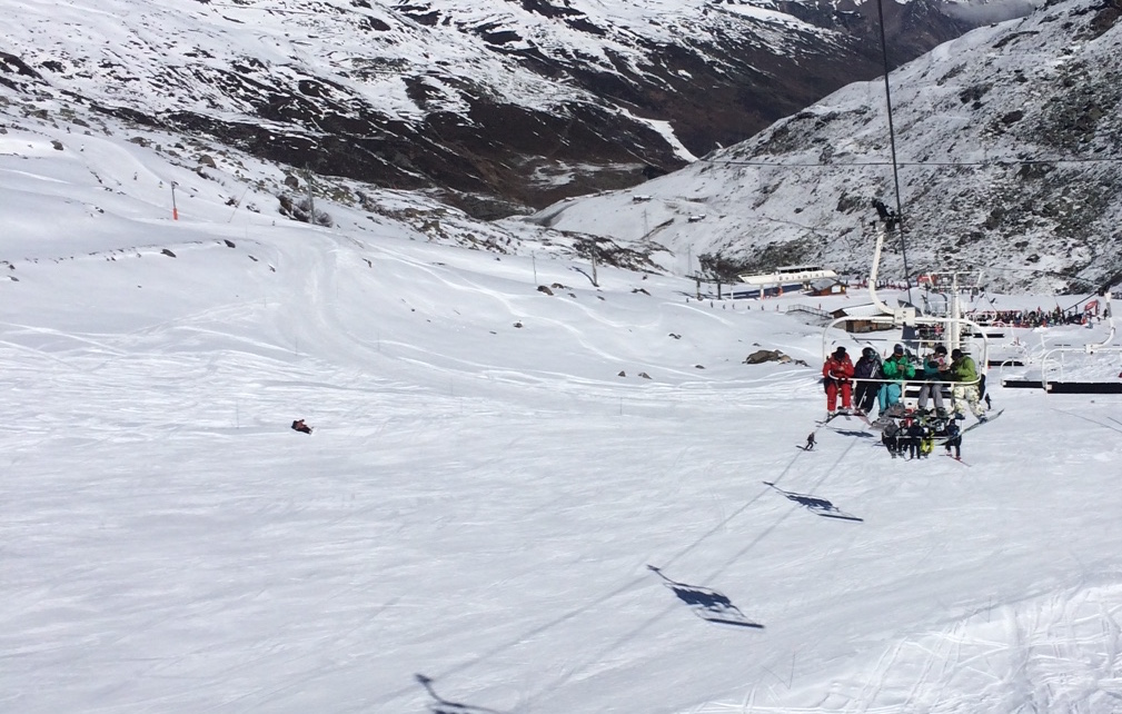 A group of people riding skis down a snow covered mountain