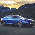 A blue car parked in front of a mountain