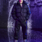 A man wearing a wet suit standing on the snow