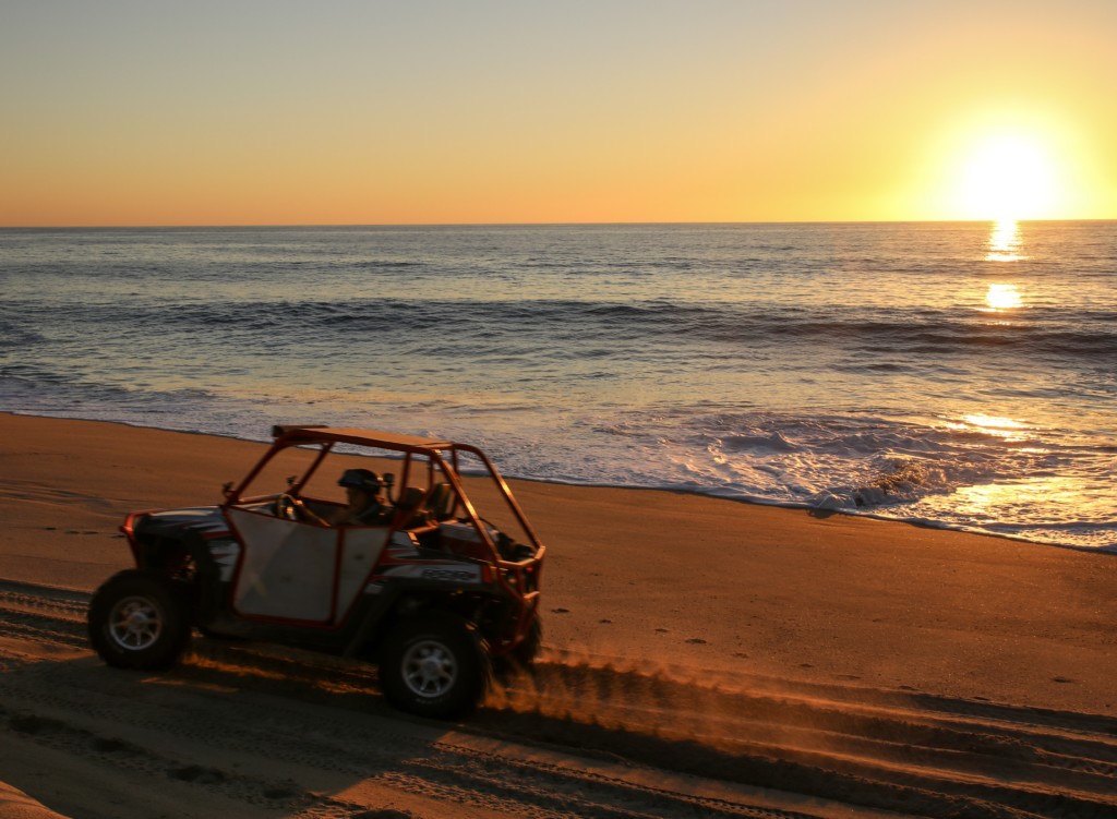 A sunset over a sandy beach next to the ocean