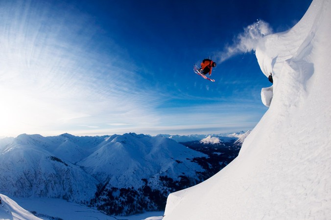 A man flying through the air on a snow covered mountain