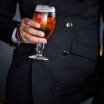 A man wearing a suit and tie holding a glass of wine
