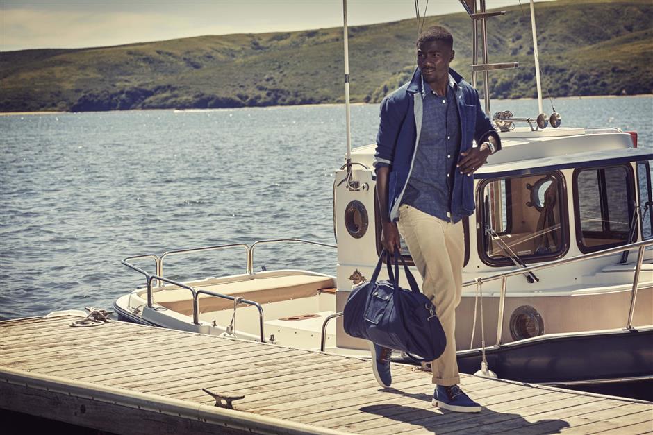 A person standing in front of a boat next to a body of water