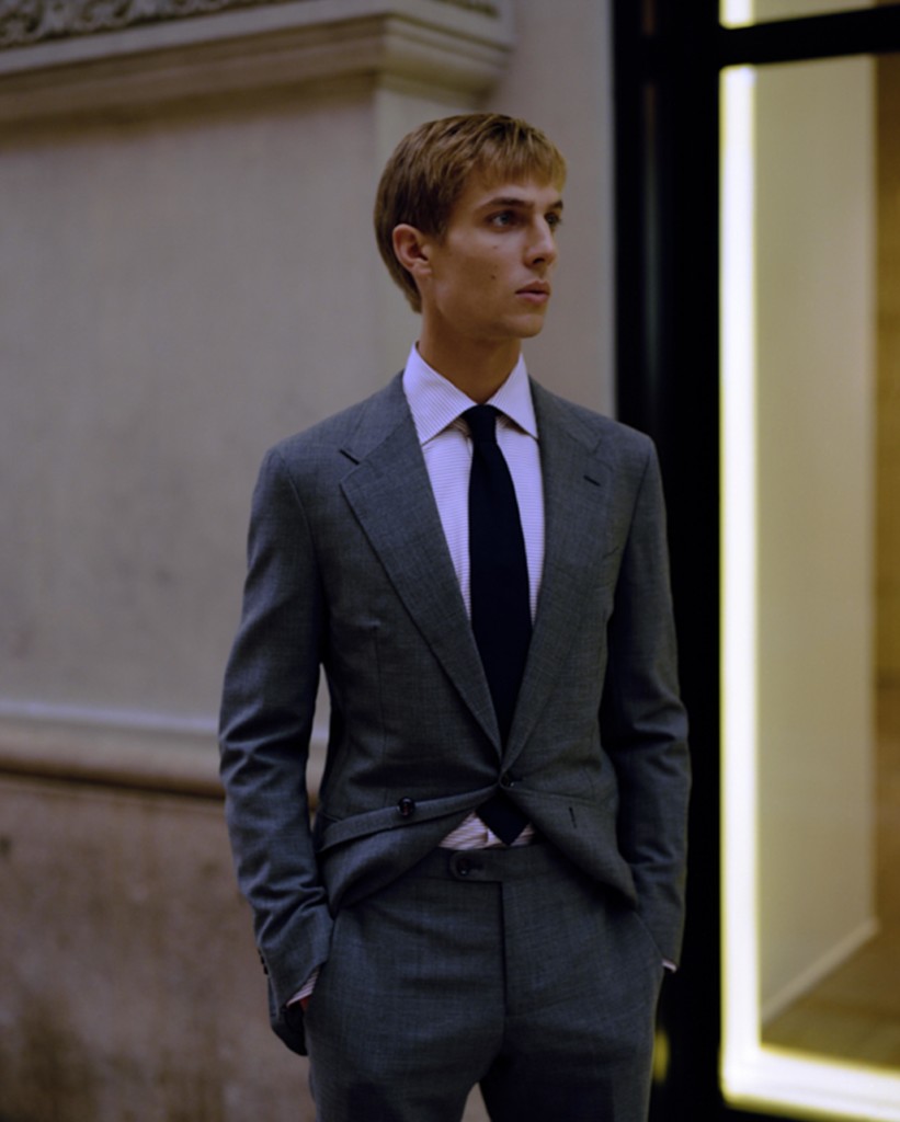 A man wearing a suit and tie standing in front of a building