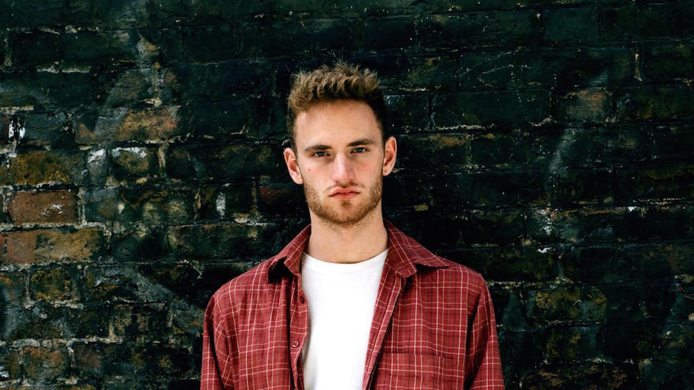 A man standing in front of a brick wall