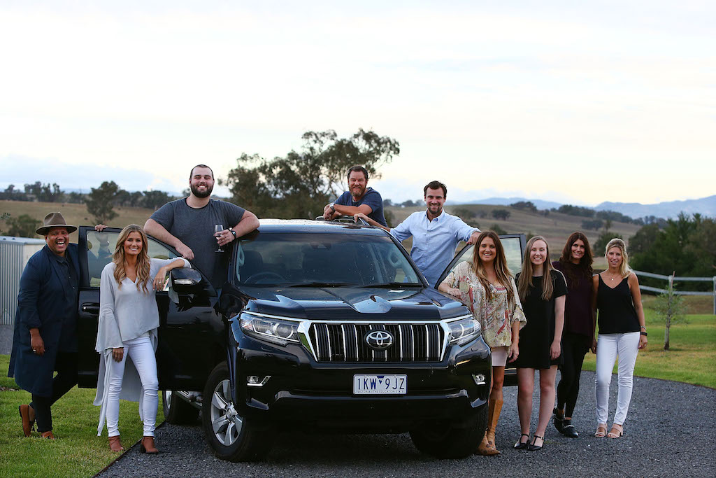 A group of people standing on top of a car posing for the camera