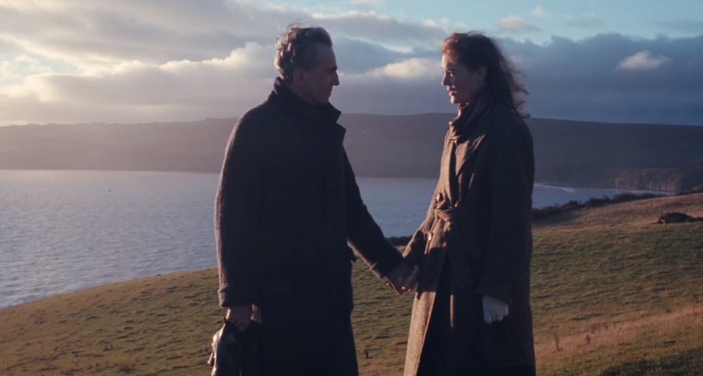 A man and a woman standing next to a body of water