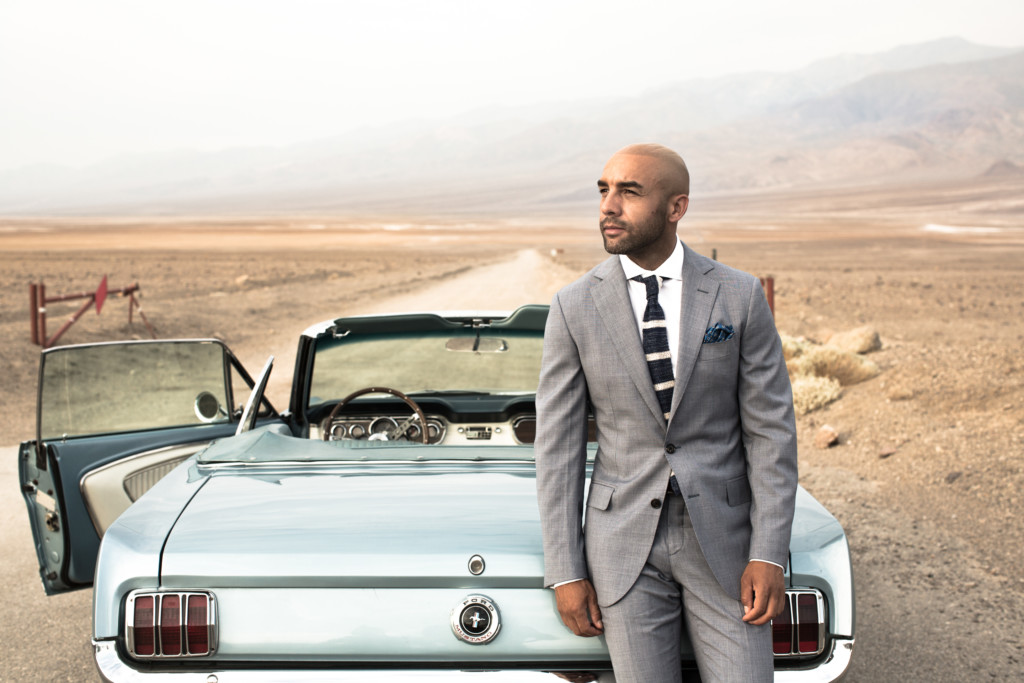 A man in a suit standing in front of a car