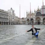 A man riding on the back of a boat next to a building