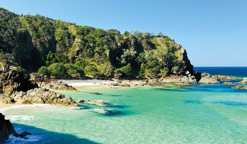 A body of water with a mountain in the ocean